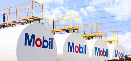 Tanques de combustible de color blanco de la marca Mobil alineados uno al lado de otro.
