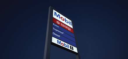 Monolito de gasolinera Mobil de noche con los productos que ofrece la estación de servicio.