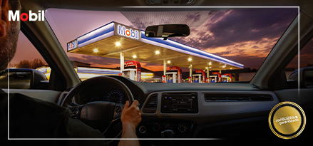 Estación de servicio Mobil vista desde dentro de un auto con un cielo nublado en el fondo.