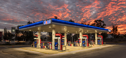 Gasolinera de la marca Mobil en un atardecer con nubes