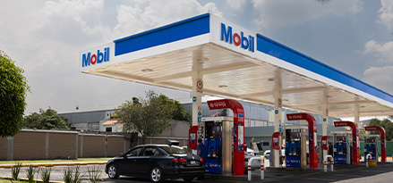 Gasolinera de la marca Mobil de color blanco y azul con un auto cargando gasolina