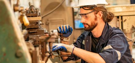 Ingeniero con casco y guantes apretando una válvula de una máquina
