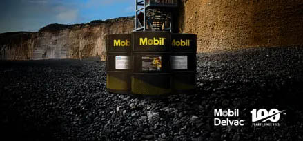 3 barriles negros en el exterior de una mina con Lubricante Mobil Delvac 100 años para la industria Minera.