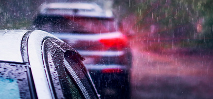 Dos autos grises formados bajo la lluvia.
