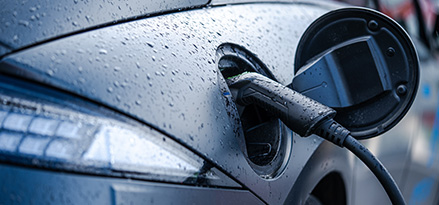 Auto eléctrico con el compartimiento de carga abierto y un enchufe de carga.